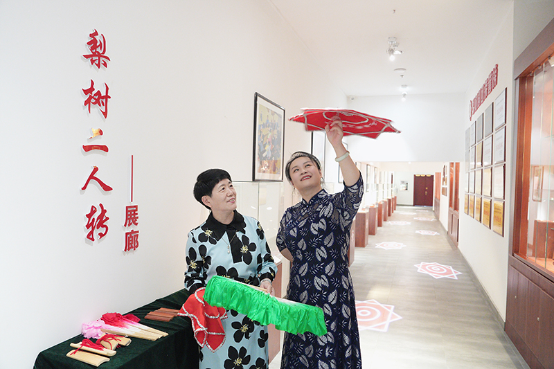 2023年6月29日，在吉林省梨樹縣地方戲曲劇團梨樹二人轉展廊，團長趙丹丹（右一）為作家龔保華講解二人轉技巧。