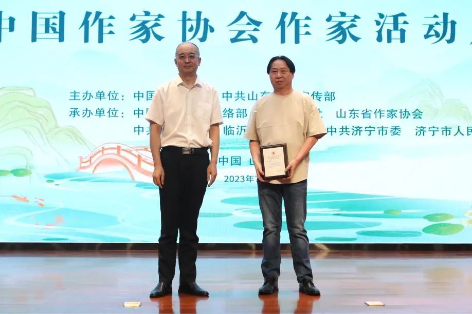 張宏森、吳義勤向參加此次“作家活動周”的中國作協會員逐一頒發專屬“入會紀念牌”